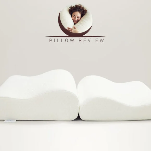 Two memory foam pillows with ergonomic contours are displayed side by side against a light beige background. The words "Pillow Review" and a logo featuring a person hugging a pillow are above them.