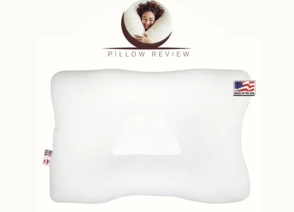 A white orthopedic pillow with an indentation in the center and a "Made in the USA" label. The top of the image features a person sleeping on a pillow with the text "Pillow Review.